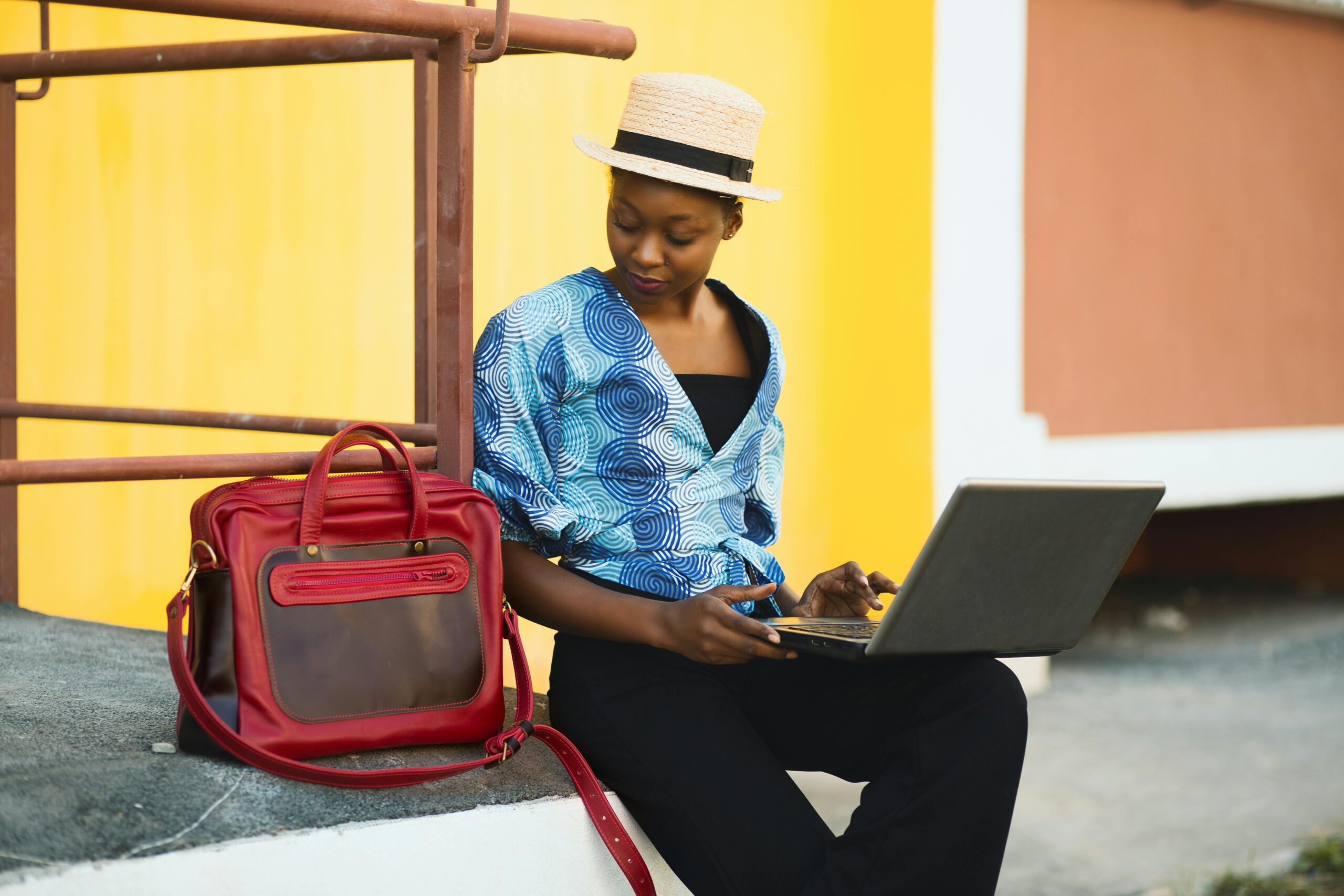 Frau, Die Neben Tasche Sitzt Und Laptop Verwendet